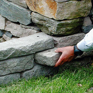 Rock lock end rock being placed on the end of a straight rock lock sitting on grass