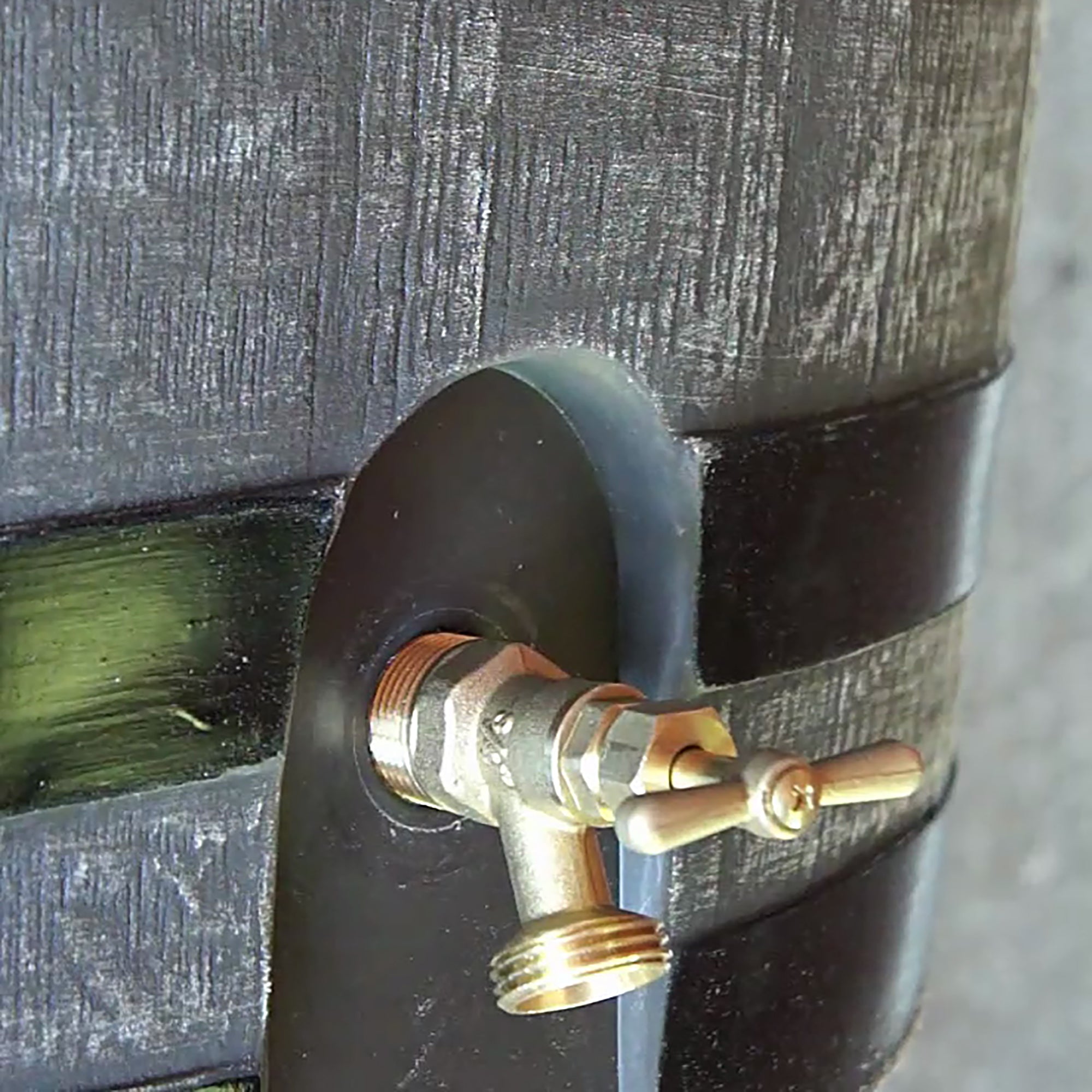 close up of brass spigot on brown with black stripes rain barrel