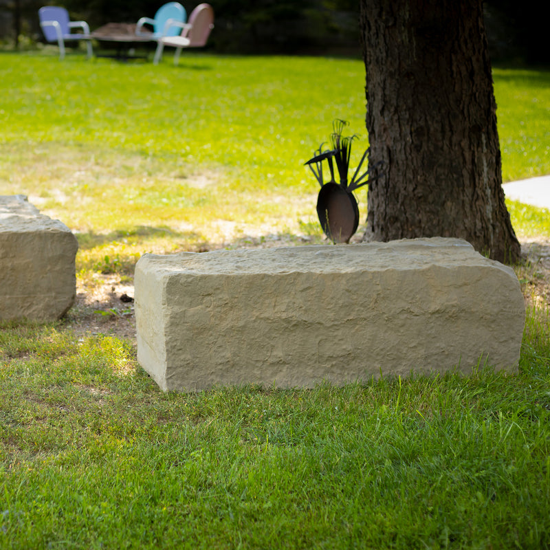 large landscape rock in sandstone on grass next to a tree